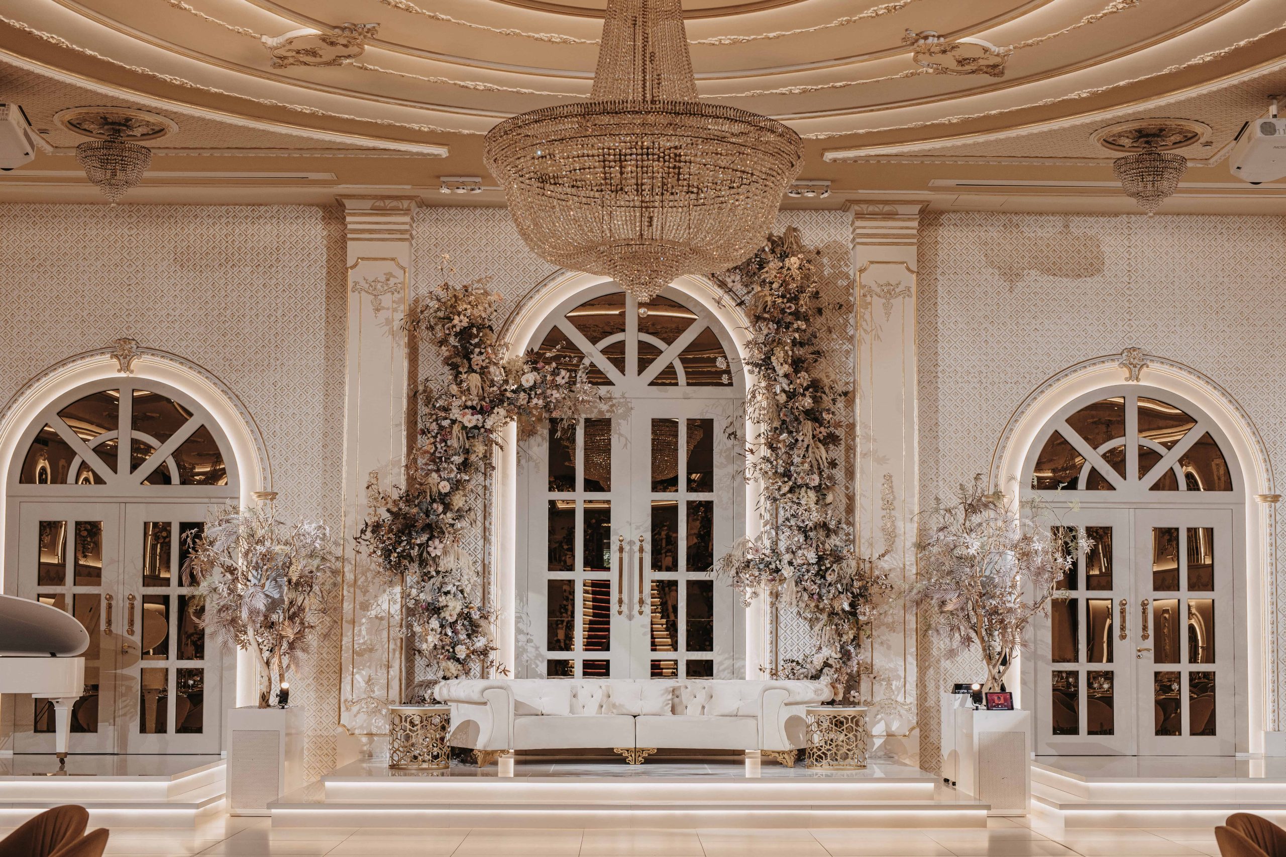 Een stijlvol podiummoment: een imposante, elegante bank vormt het middelpunt in de majestueuze setting van de grote zaal – perfect voor onvergetelijke ceremonies en fotoshoots